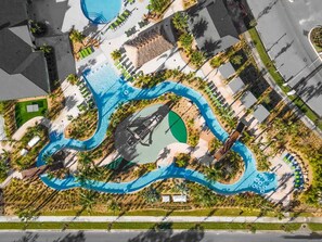 An aerial view of a resort with multiple swimming pools, a central water feature, and surrounding palm trees. - Amazing Resort Near Disney 4BR Townhome (Kissimmee)