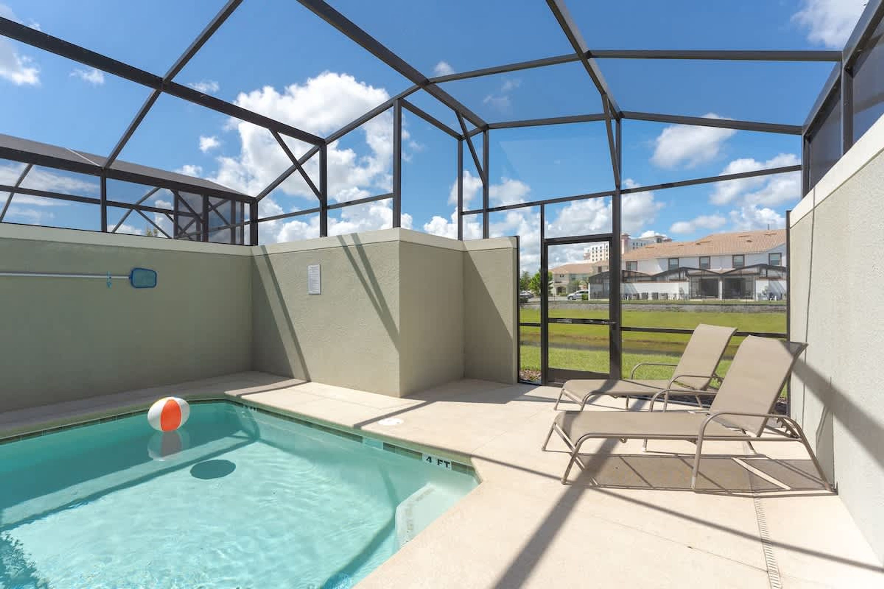 An indoor swimming pool with clear blue water, a lifeguard chair, and a poolside lounge area with two chairs.