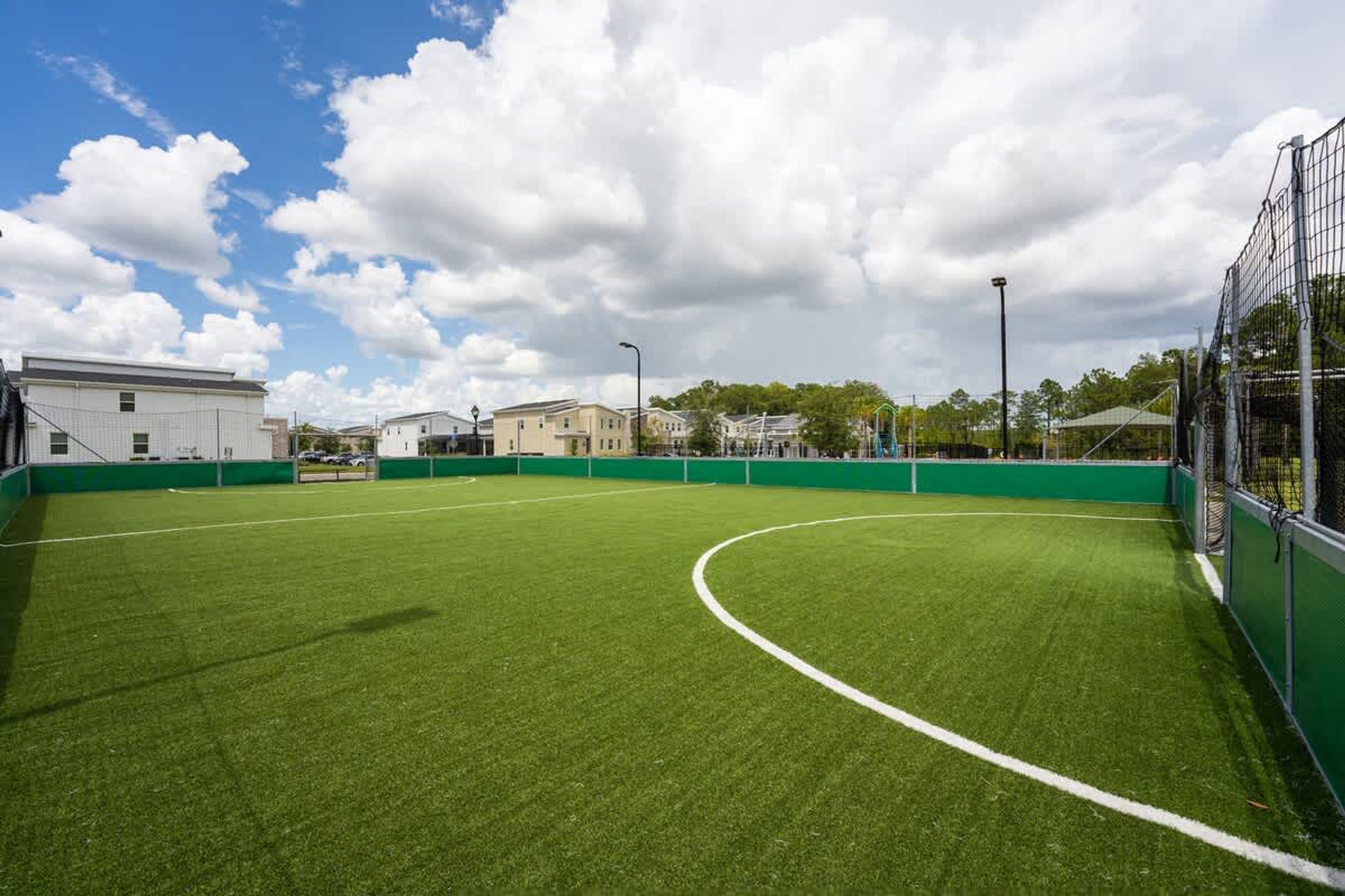 Ein Fußballfeld mit grüner Rasenfläche, Toren und einer Umzäunung.