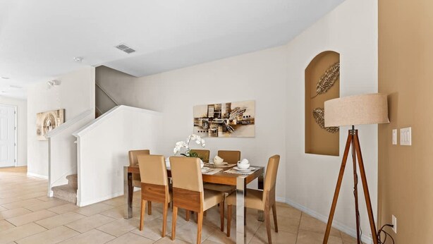 Un coin repas avec une table et des chaises en bois, une lampe et un tableau au mur.