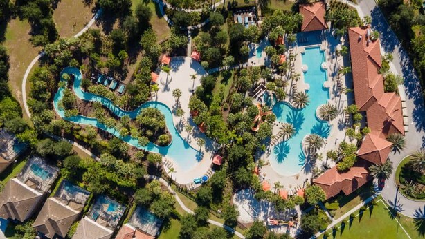 An aerial view of a resort with multiple swimming pools, lush greenery, and a variety of buildings.