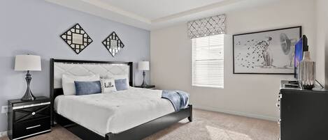 Un dormitorio con cama, mesitas de noche, cómoda y decoración en la pared.