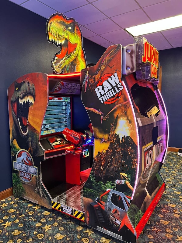 A Jurassic Park themed arcade machine with a dinosaur graphic and the name 'Raw Thrills'.