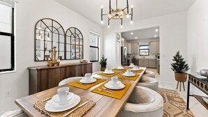 A modern dining area with a long wooden table set for six, a chandelier, and a kitchen in the background. - Luxury Decor 6BR at Storey Lake Sleeps 16 Sl2945 (Kissimmee)