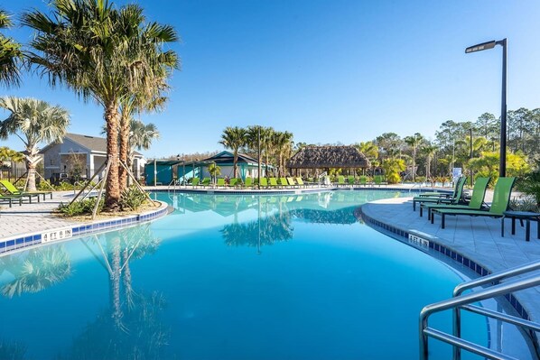 A swimming pool with lounge chairs, palm trees, and a building in the background. - Luxury Decor 6BR at Storey Lake Sleeps 16 Sl2945 (Kissimmee)