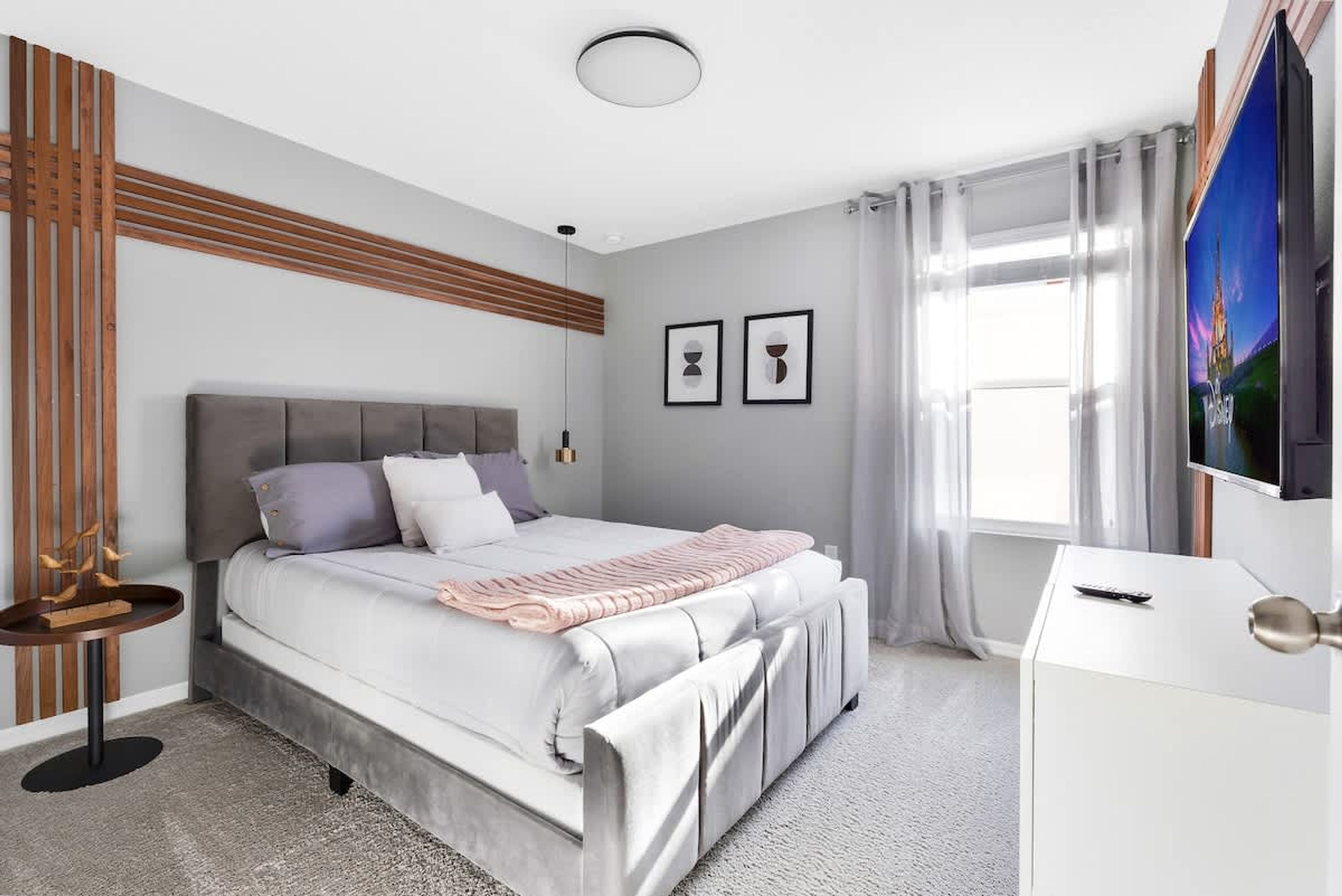 A modern bedroom with a bed, bedside table, and a TV on a dresser.