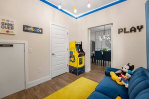 Una stanza con un divano blu, una macchina arcade gialla e una porta con la scritta 'PRIVATE'.