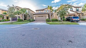 A residential street with houses, a driveway, and a parked SUV. - Pet Friendly Amazing 5 BR Sleeps 10 Ww2116 (Kissimmee)