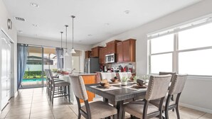 A modern kitchen with wooden cabinets, a dining table with chairs, and a view of a pool through glass doors. - Pet Friendly Amazing 5 BR Sleeps 10 Ww2116 (Kissimmee)