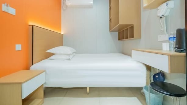 A compact hotel room with a bed, bedside table, and a small desk area. - Puhua Hotel (Shanghai)