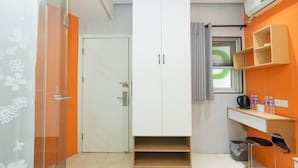 A compact room with a wardrobe, a small seating area, and a window with a curtain. - Puhua Hotel (Shanghai)