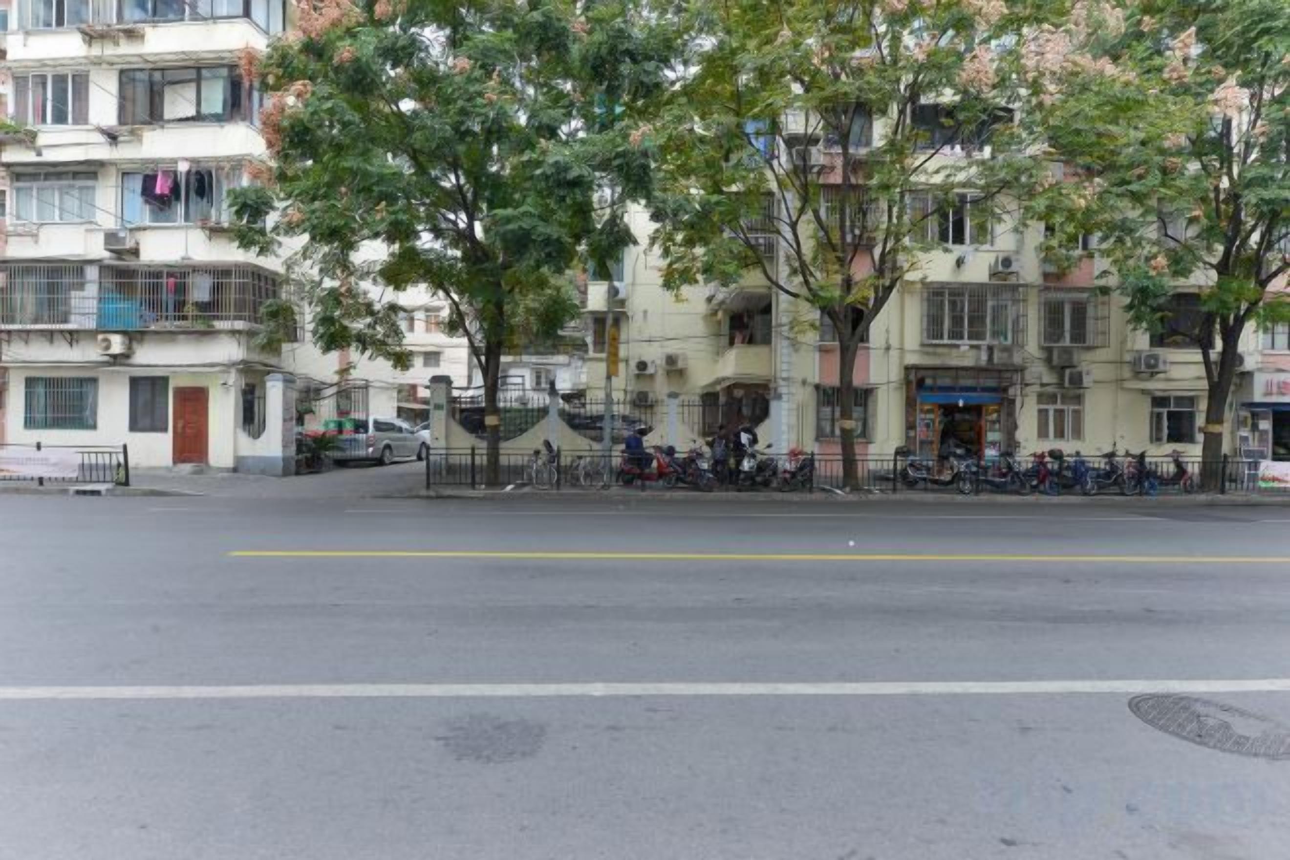 A street with buildings, trees, and parked motorcycles.