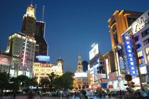 A cityscape with illuminated buildings and a prominent clock tower. - Puhua Hotel (Shanghai)