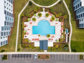 Vista aérea de un edificio residencial con piscina, zonas de descanso y aparcamiento.