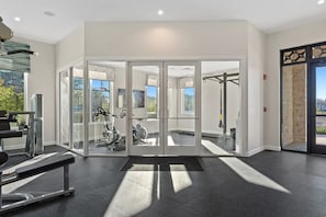 Une salle de sport moderne dotée de portes vitrées, d’équipements d’exercice et offrant une vue sur l’extérieur.