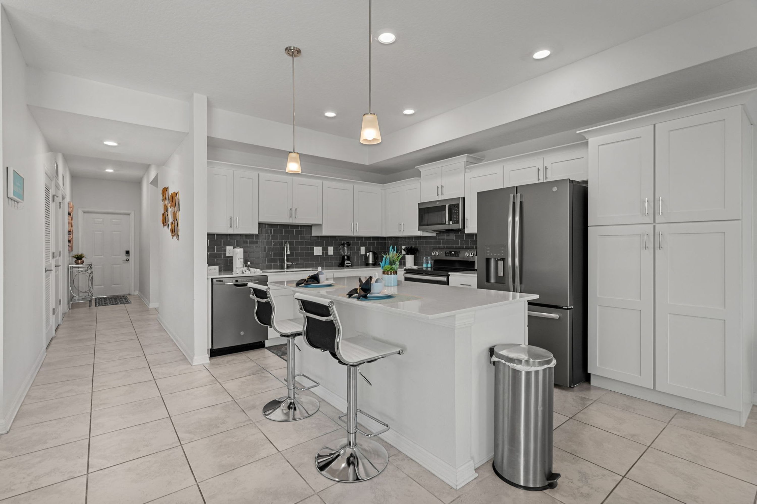 A modern kitchen with white cabinets, stainless steel appliances, and a central island with bar stools.