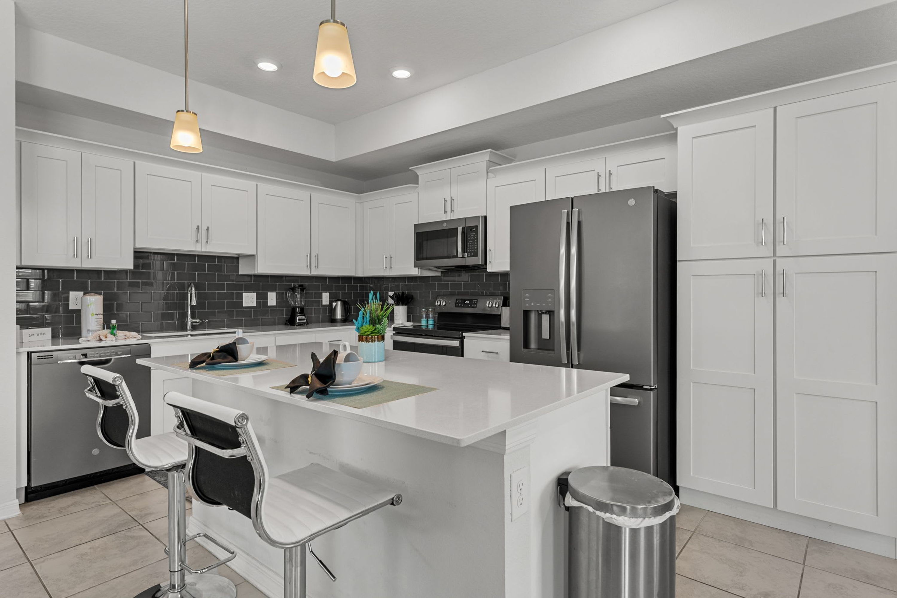 A modern kitchen with white cabinets, stainless steel appliances, and a central island with bar stools.