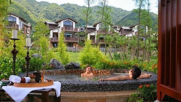 A hot spring area with two people relaxing, surrounded by lush greenery and a mountainous backdrop. - Country Garden Hot Spring Holiday Villa (Fogang)