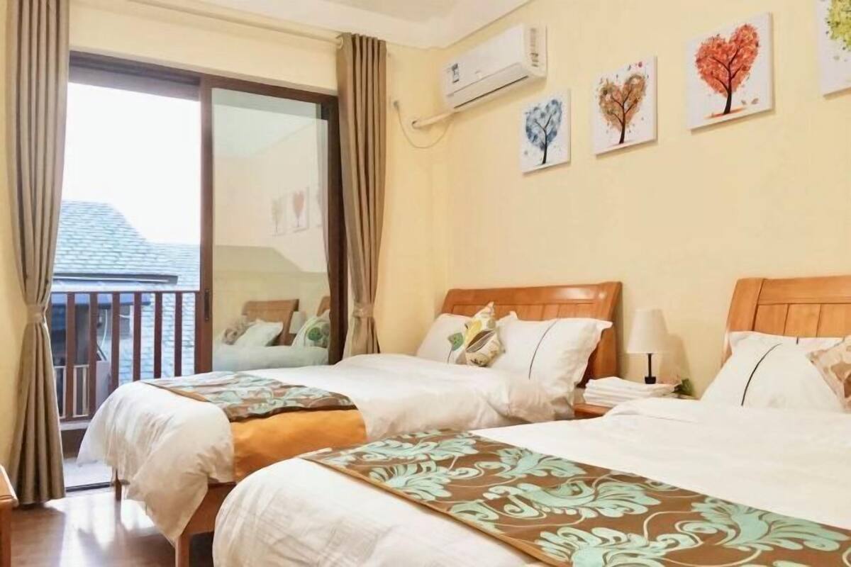 A hotel room with two beds, a balcony, and wall art.