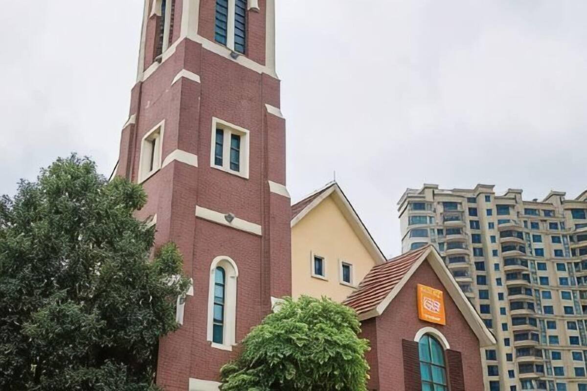 A church with a tall bell tower and a smaller building with a sign.