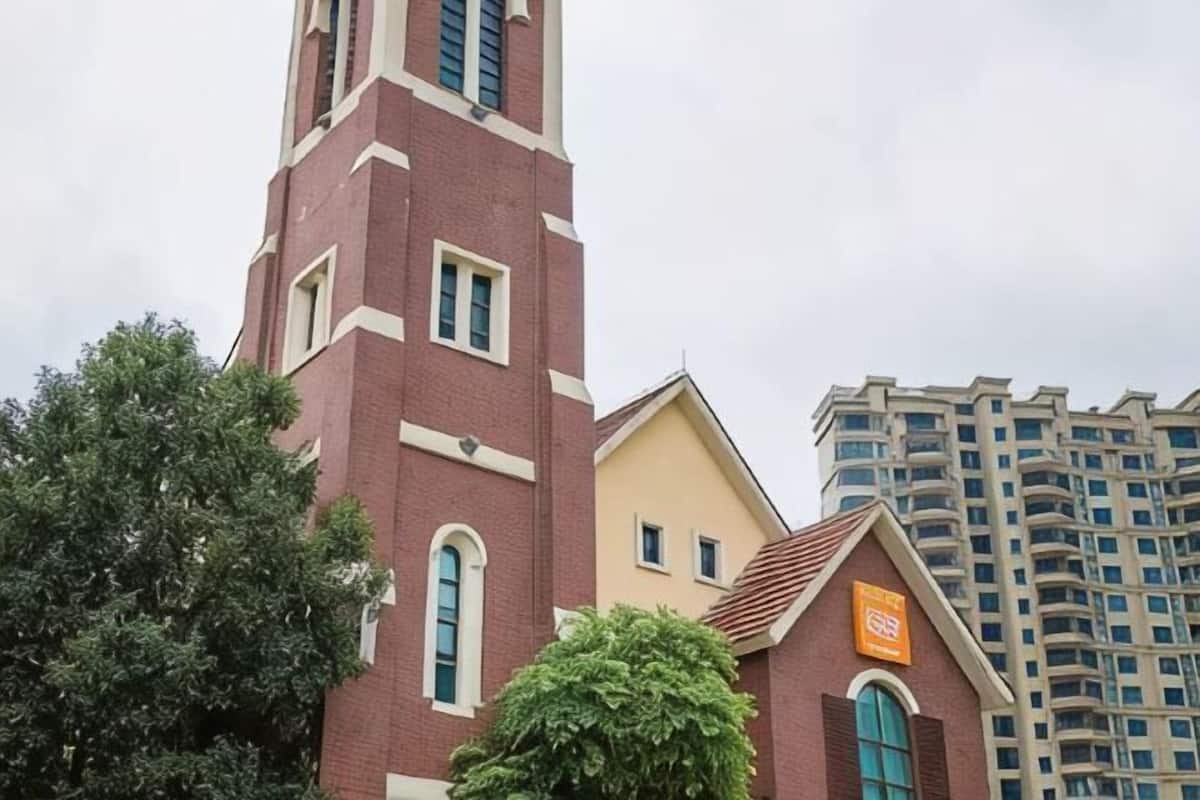 Een kerk met een hoge klokkentoren en een kleiner gebouw met een bord.
