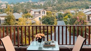 A balcony with a table set for tea, overlooking a residential area with houses and trees. - Country Garden Hot Spring Holiday Villa (Fogang)