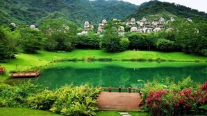 A resort with multiple villas nestled among lush greenery, a pond, and a wooden bridge. - Country Garden Hot Spring Holiday Villa (Fogang)