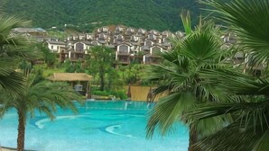 A resort with a swimming pool, palm trees, and a mountainous backdrop. - Country Garden Hot Spring Holiday Villa (Fogang)