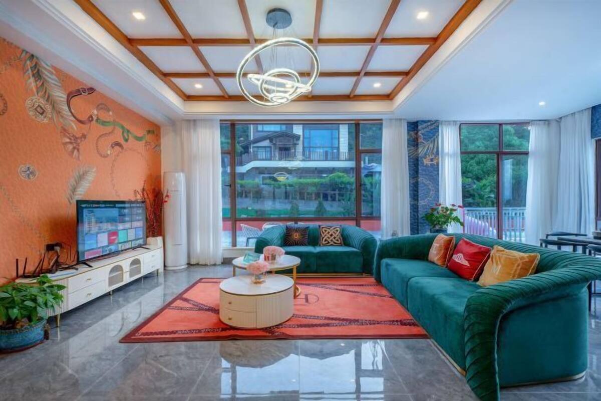 A spacious living room with a large green sofa, a coffee table, and a television on a white cabinet.