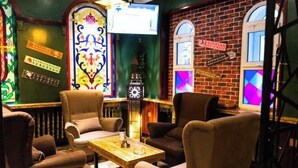 A cozy seating area with cushioned chairs and a wooden table, surrounded by decorative stained glass windows and a brick wall. - Bremen Hotel ( Central Street) (Harbin)