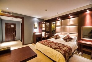 Une chambre d’hôtel avec un grand lit, un bureau, un miroir et une armoire.