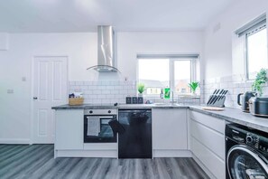 A modern kitchen with a dishwasher, oven, and washing machine. - Stylish Modern 3BR | Wigan Escape | Free Parking (Greater Manchester)