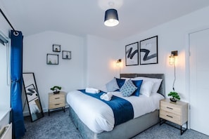 A modern bedroom with a bed, bedside tables, and wall art. - Stylish Modern 3BR | Wigan Escape | Free Parking (Greater Manchester)