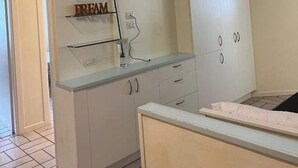 Una cocina con armarios blancos, una estantería de vidrio y una encimera.