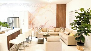 A modern living room with a sofa, coffee table, and bar area. - The Cozy Palm House (Homestead)