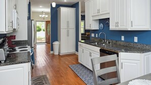 A modern kitchen with white cabinets, granite countertops, and a wooden floor. - Charming 3-bedroom house with AC, WiFi located in Supply NC near Holden Beach (supply)