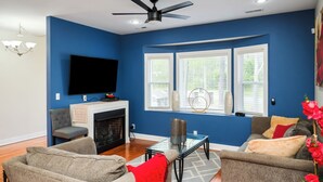 A living room with a fireplace, two sofas, a TV, and a window with blinds. - Charming 3-bedroom house with AC, WiFi located in Supply NC near Holden Beach (supply)