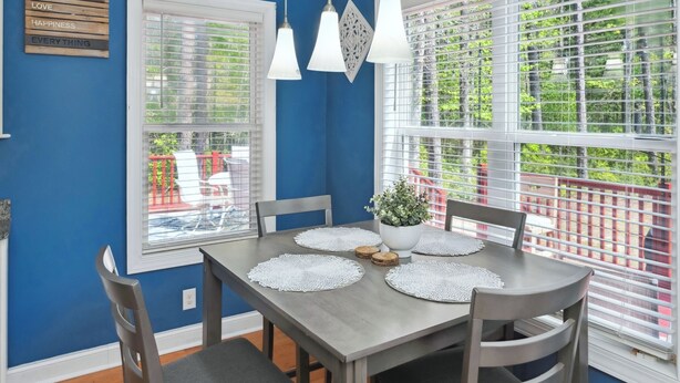 A dining area with a blue wall, white blinds, and a table set with placemats and a potted plant. - Charming 3-bedroom house with AC, WiFi located in Supply NC near Holden Beach (supply)