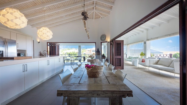 A spacious kitchen with white cabinets and a wooden dining table. - Mi Cuna Stays Collection (Jan Thiel)