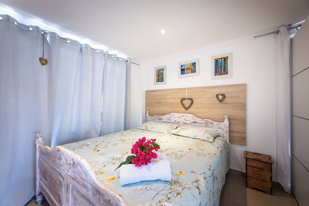 A bedroom with a wooden headboard, floral bedding, and a heart-shaped decoration on the wall.