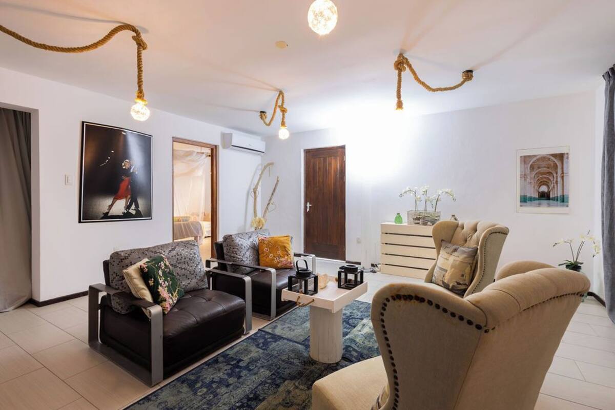 Una sala de estar moderna con sofá, sillones, una mesa de centro y plantas decorativas.