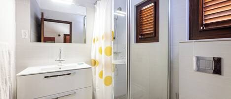 Une salle de bain équipée d’une douche, d’un lavabo, d’un miroir et de toilettes.