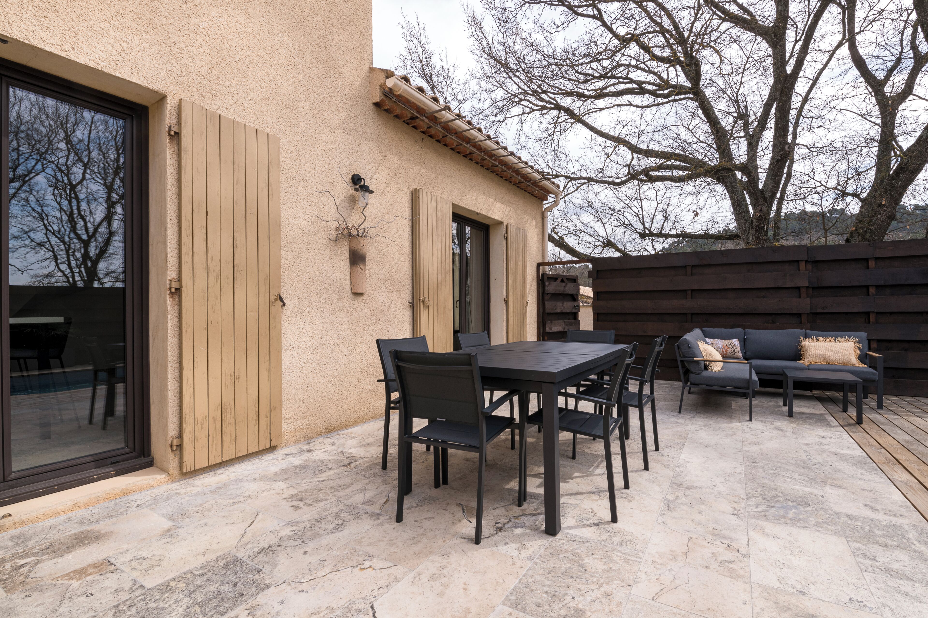An outdoor patio with a table and chairs, a sofa, and a pergola.