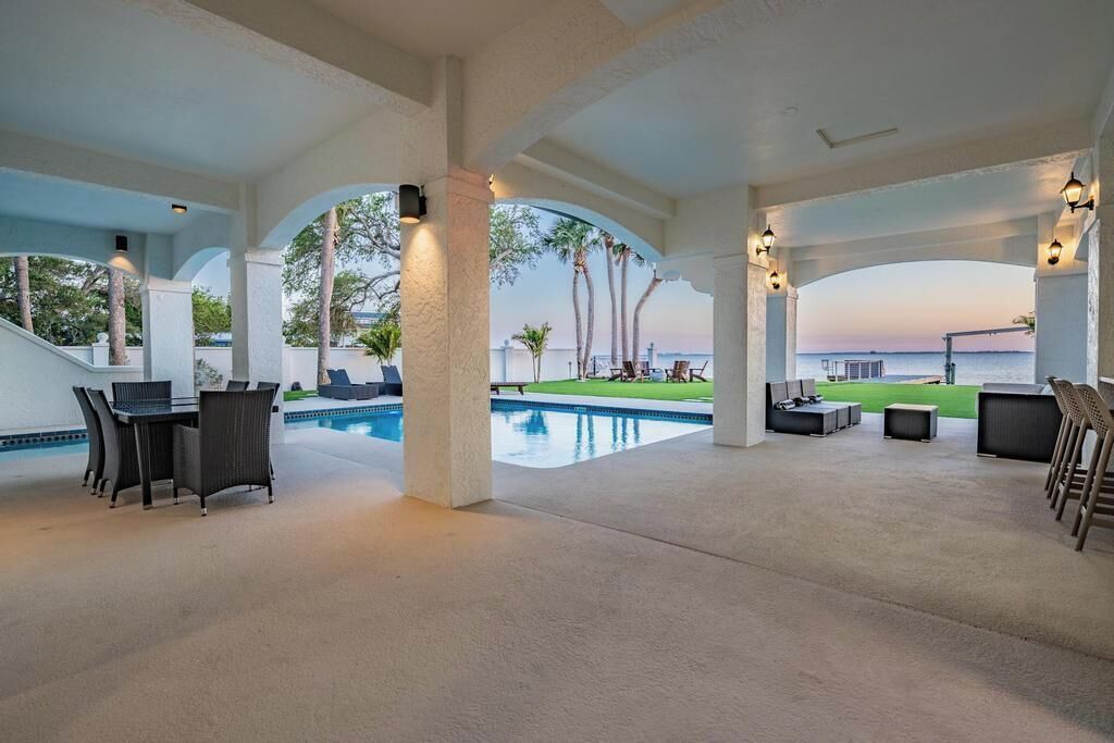 Un espace extérieur aménagé avec une terrasse, une piscine, des sièges et une vue sur la mer.
