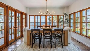 Un vaste espace dédié à la salle à manger, avec un îlot central, des chaises en bois et un lustre.