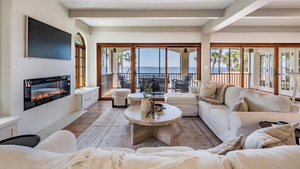 Un salon spacieux doté d’une cheminée, de sièges confortables et d’un balcon offrant une vue sur la mer.