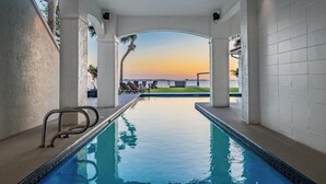 A pool area with a view of the sunset, white walls, and a few lounge chairs. - NEW Waterfront 6 bedroom home with large pool and luxurious outdoor living area! (Palm Harbor)
