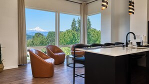 A modern kitchen with a large island, two brown leather chairs, and a view of a mountain. - Two-bedroom suite, Mt Hood views, downtown White Salmon, suite 30 (White Salmon)