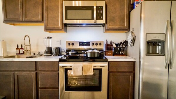A modern kitchen with stainless steel appliances, including a microwave, stove, and refrigerator. - Chic New York Style 10 Minutes to SNA Disneyland (Santa Ana)