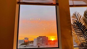 A cityscape view from a window with blinds, featuring buildings and a sunset. - New York Style Home 10 Minutes To SNA Disneyland (Santa Ana)